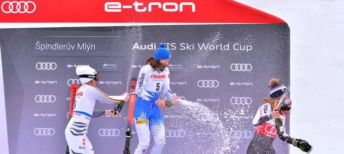Mikaela Shiffrinová utíká před sprškou šampaňského od vítězné Petry Vlhové a druhé Němky Rebensburgové