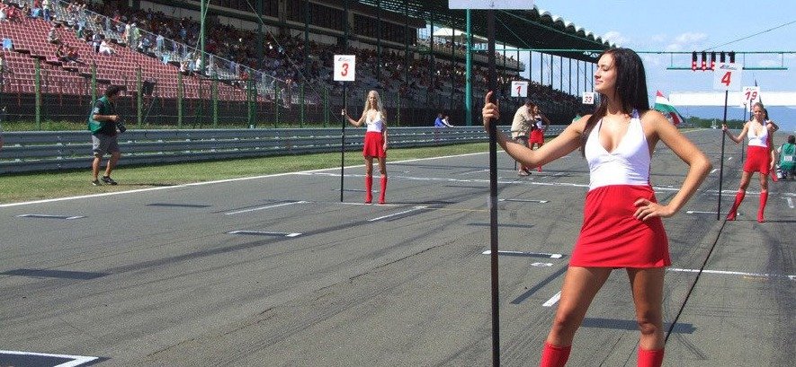 Grid girls čekají až se na startu seřadí závodníci