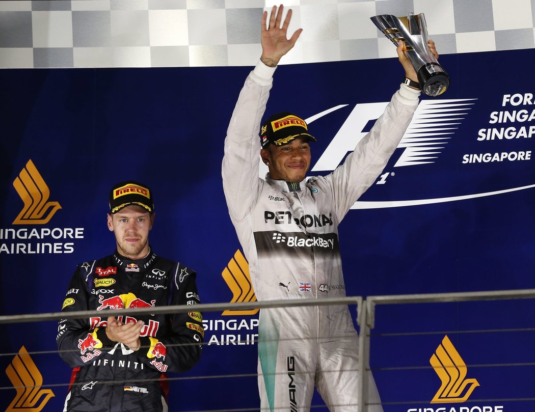 Vítězný Hamilton se raduje s trofejí, přihlíží Sebastian Vettel.