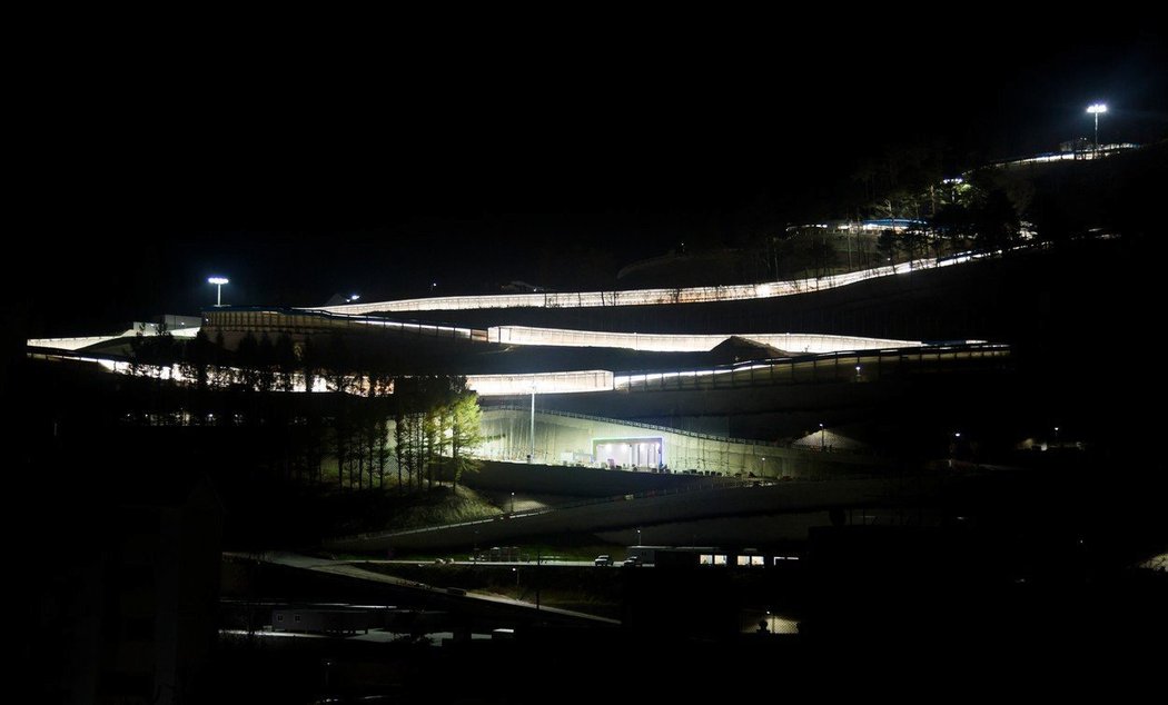 Noční pohled na koryto, kde se během olympiády uskuteční souboje o medaile v bobech, saních a skeletonu