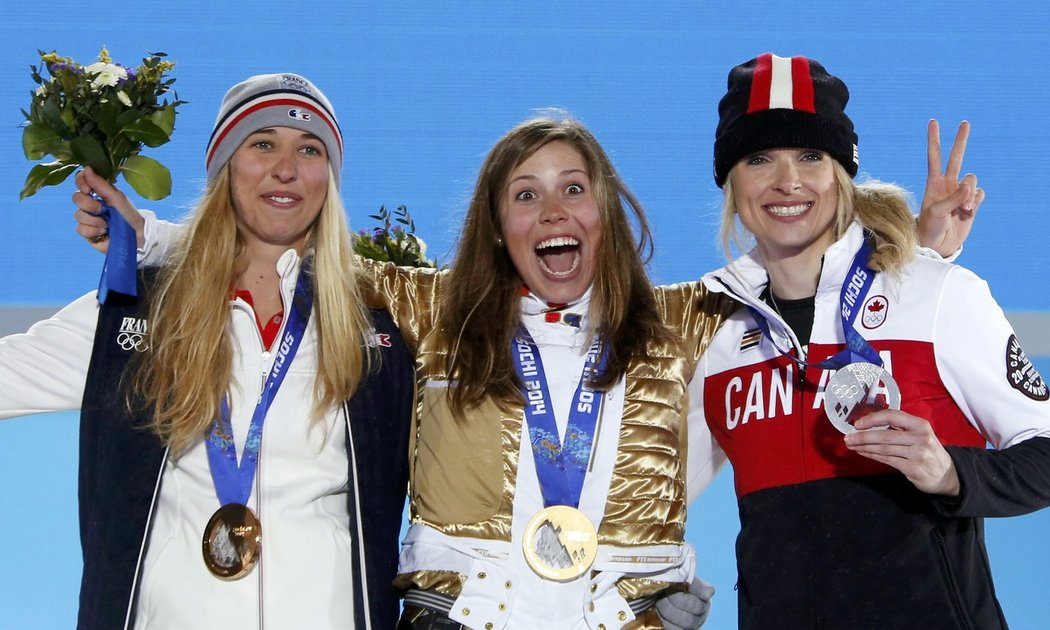 Vysmátá Eva Samková se zlatou medailí a ve zlaté bundě, vlevo bronzová Chloe Trespeuchová, vpravo stříbrná Dominique Maltaisová
