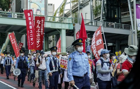 Skupina protestujících Japonců proti olympiádě v Tokiu pod dohledem policistů