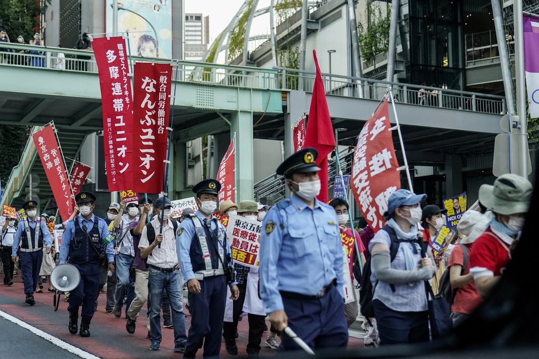 Skupina protestujících Japonců proti olympiádě v Tokiu pod dohledem policistů