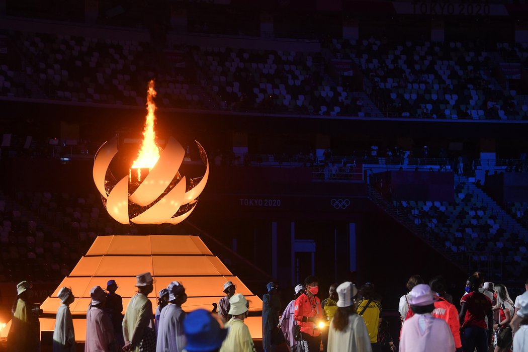 Sportovci na slavnostním zakončení sledují olympijský oheň