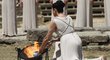 Řecká herečka Ino Menegaki jako Kněžka ohně zapaluje pomocí parabolického zrcadla olympijský oheň