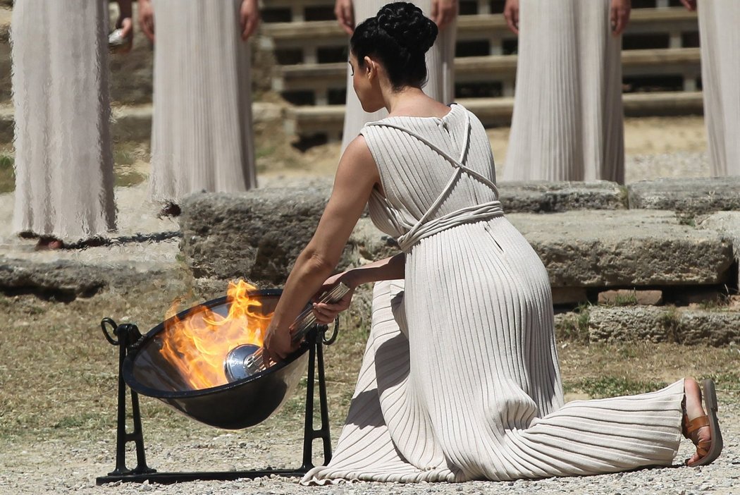 Řecká herečka Ino Menegaki jako Kněžka ohně zapaluje pomocí parabolického zrcadla olympijský oheň