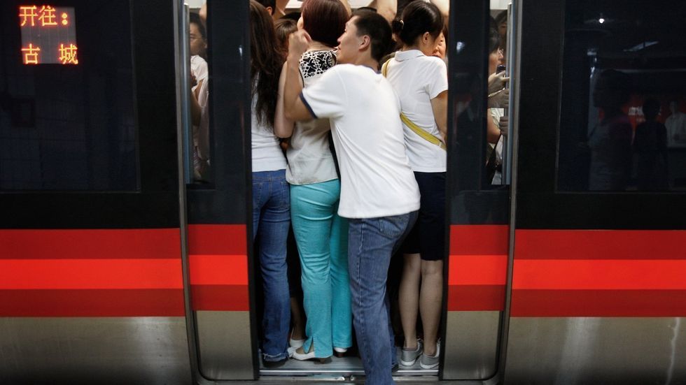 Cestující se snaží vmáčknout do přeplněného vagonu metra v Pekingu.