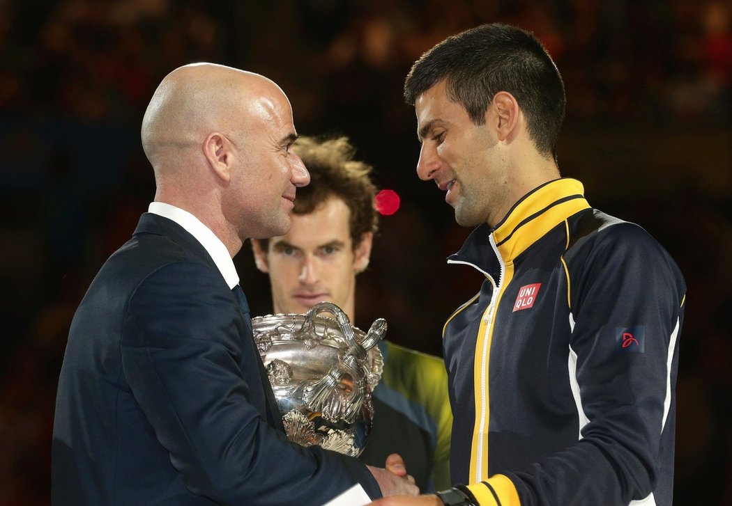 Andre Agassi předává Novaku Djokovičovi pohár pro vítěze Australian Open v roce 2013. Vzadu přihlíží poražený finalista Andy Murray.