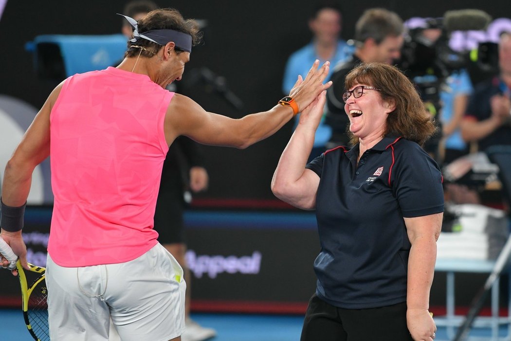 Rafael Nadal povzbuzuje jednu z hasiček, Deb Borgovou, kterou si tenisové hvězdy vytáhly na exhibici v Melbourne