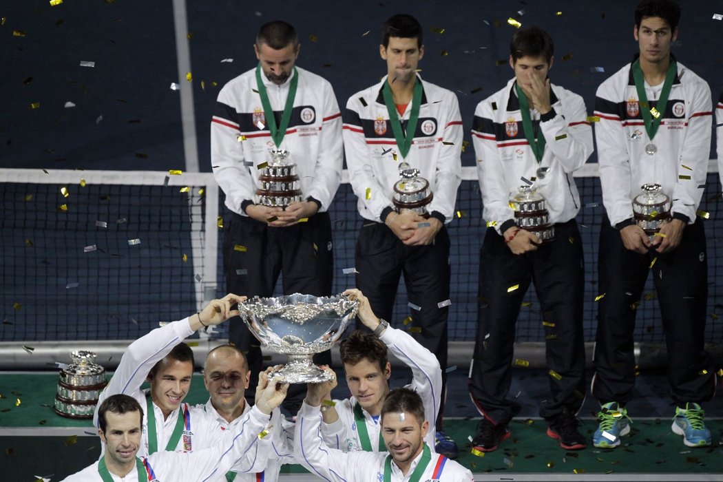 Srbští tenisté vzadu smutně sledují českou radost s pohárem