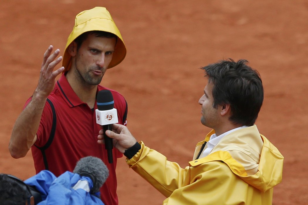 Novak Djokovič pobavil fanoušky, když po výhře odpovídal ve žluté nepromokavé čepici, kterou sebral Fabrici Santorovi