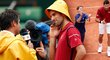 Novak Djokovič se po výhře v osmifinále French Open dobře bavil: slavil s podavačem míčků a Fabrici Santorovi sebral žlutý klobouček proti dešti