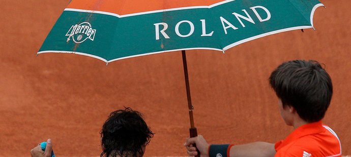 Rafael Nadal se suší v průběhu finále French Open, zatímco nad ním musel podavač míčků držet deštník