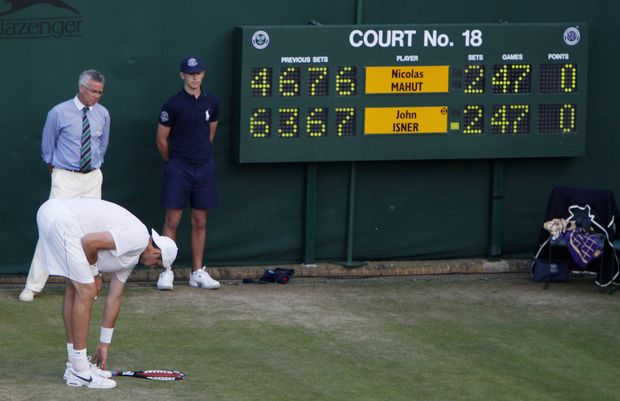 Isner sbírá unaveně z dvorce raketu. Isner sbírá unaveně z dvorce raketu.
