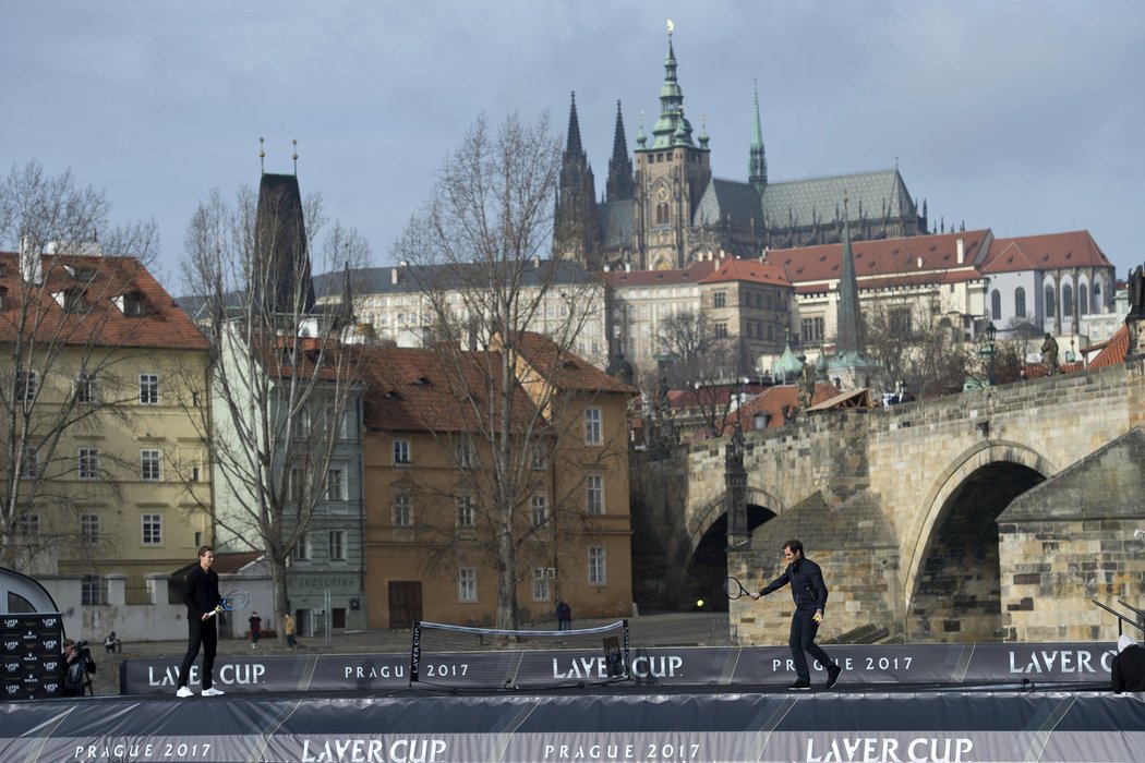 Tomáš Berdych (vlevo) a Roger Federer si pinkají na lodi pod Karlovým mostem s výhledem na Pražský hrad