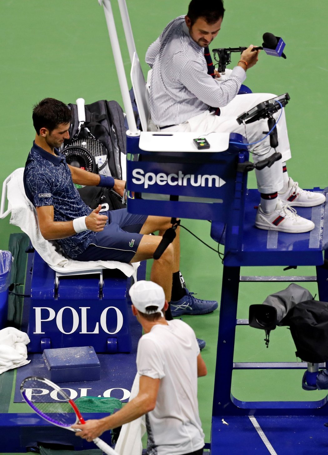 John Millman se odchází převléct během zápasu s Novakem Djokovičem na US Open