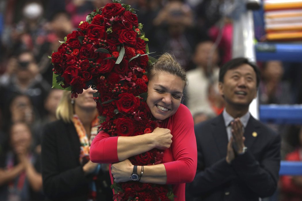 Simona Halepová objímá obří květinovou jedničku, která symbolizuje její posun na první místo světového žebříčku
