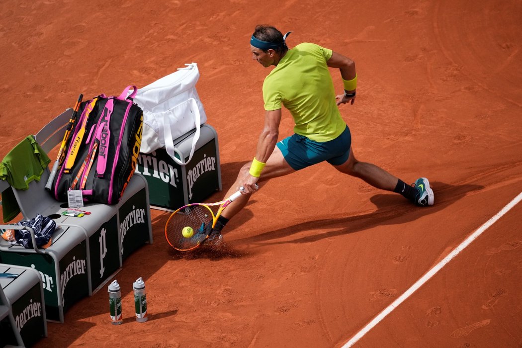 Rafael Nadal během úderu těsně u hráčské lavičky