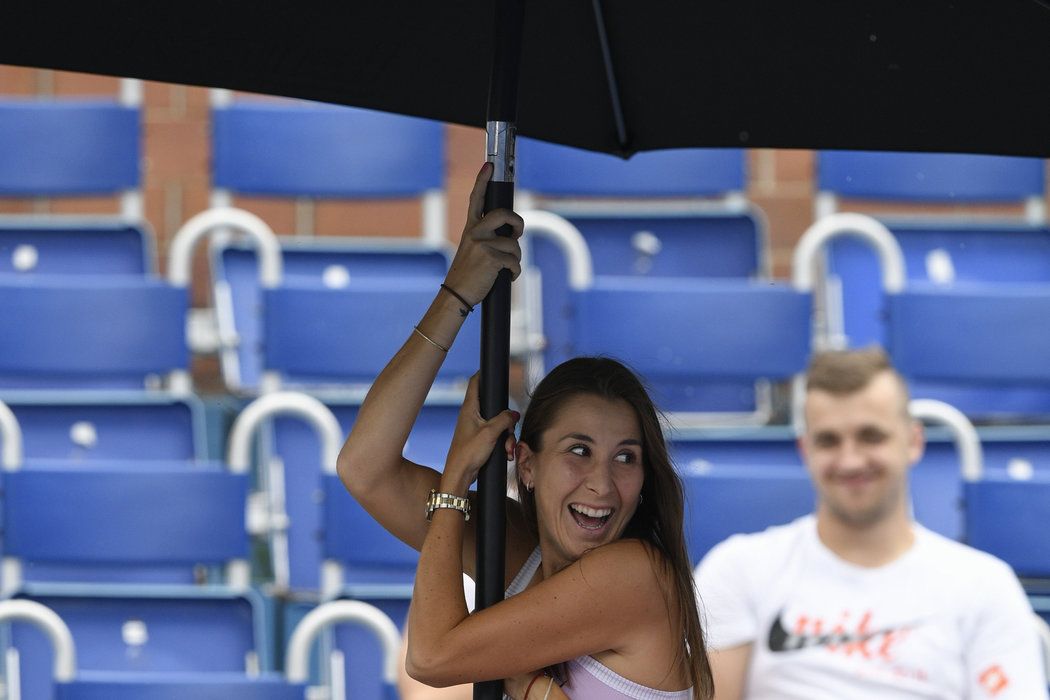 Belinda Bencicová drží slunečník při poryvu větru