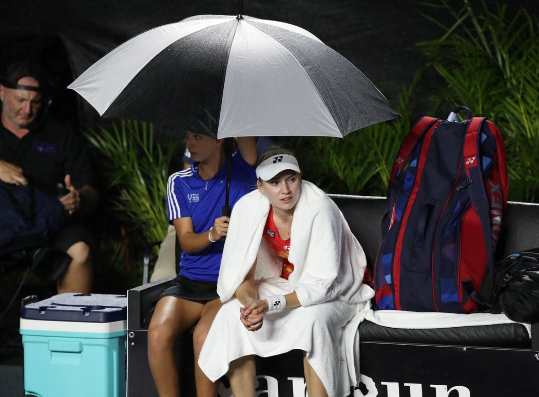 Elena Rybakinová pod deštníkem po přerušení zápasu se Sabalenkovou