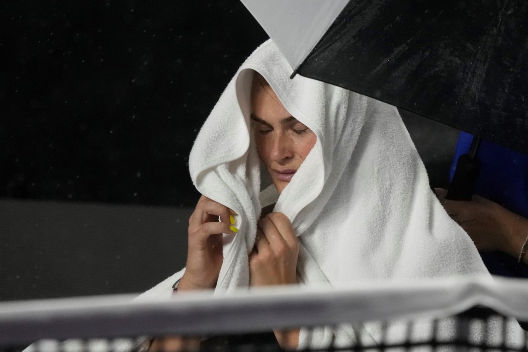Aryna Sabalenková se zahaluje do ručníku při deštivém počasí