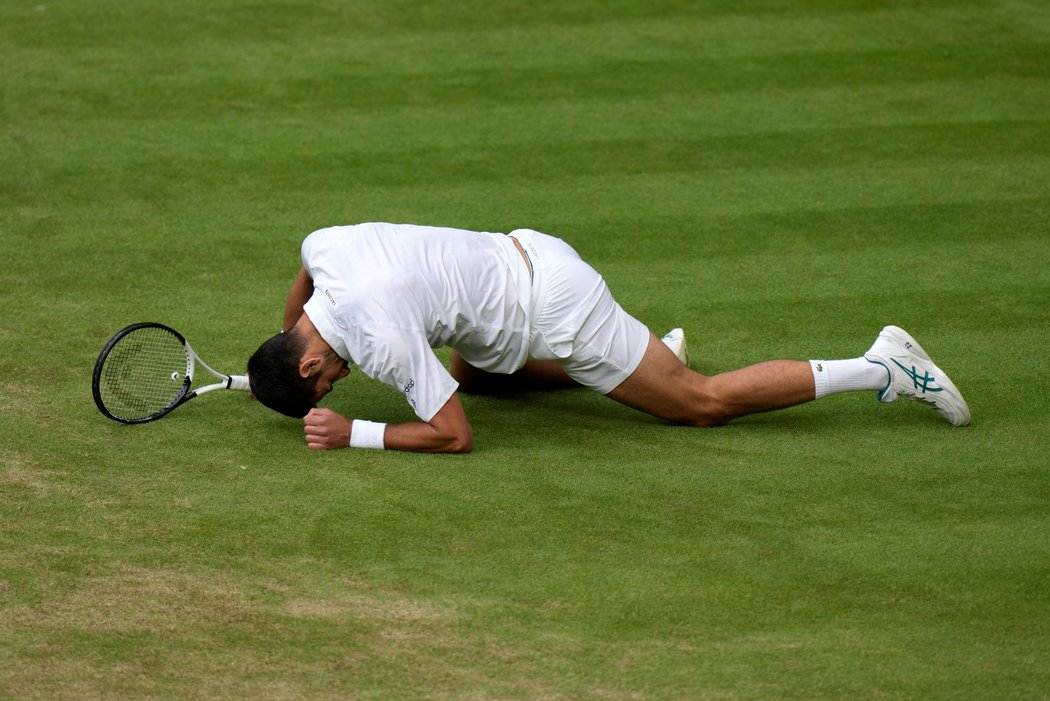 Novak Djokovič se těžce zvedá z trávníku během finále Wimbledonu