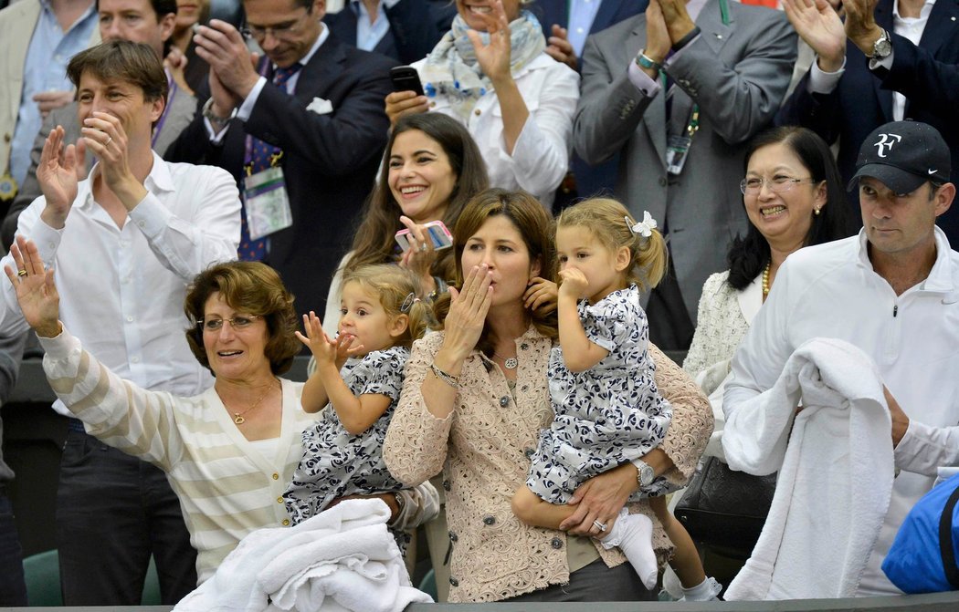 Mirka Federerová (uprostřed) posílá spolu s dcerkami vzdušný polibek svému muži, který právě po sedmé vyhrál Wimbledon