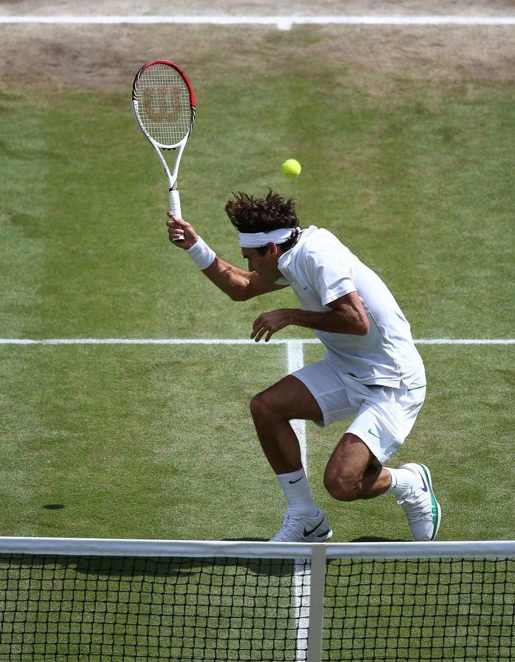 Roger Federer se uhýbá před míčkem vypáleným z rakety Andyho Murrayho ve finále Wimbledonu