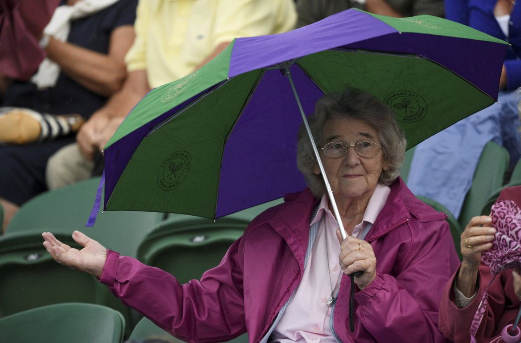 Divačka s deštníkem zkouší, jak to vypadá s deštěm během prvního dne Wimbledonu