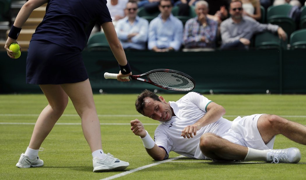 Podavačka míčků asistuje Radku Štěpánkovi u jeho zvedání po pádu v duelu prvního kola Wimbledonu proti Nicku Kyrgiosovi