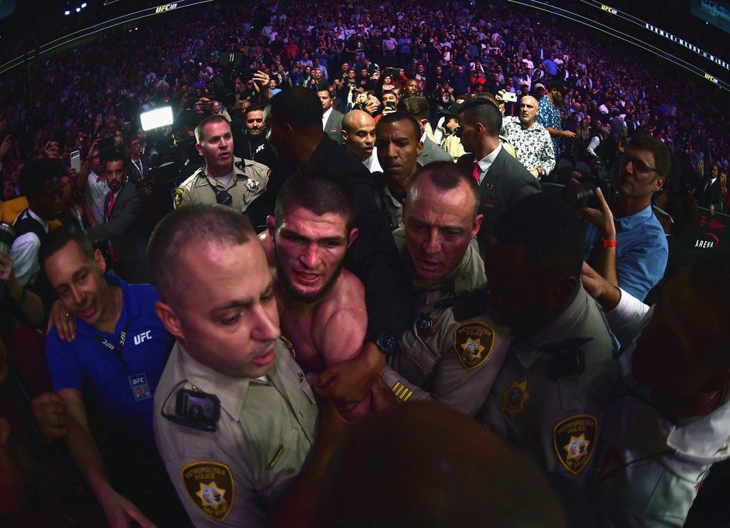 Vítěz Khabib Nurmagomedov opouští v doprovodu ochranky oktagon ve Vegas.