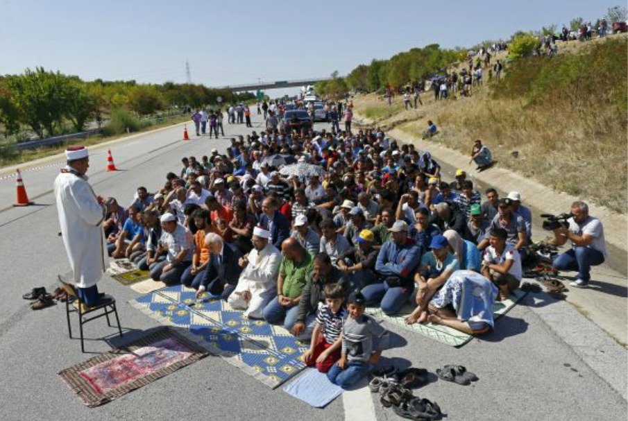 Muslimská modlitba uprchlíků na silnici cestou za svobodou.