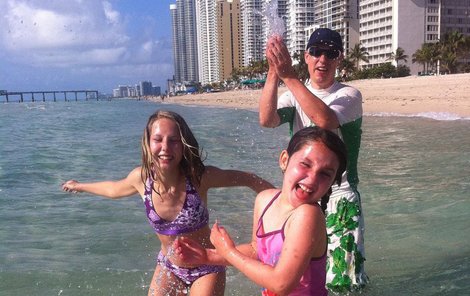 Stanislav Gross v kšiltovce a slunečních brýlích dovádí s dcerami v oceánu.