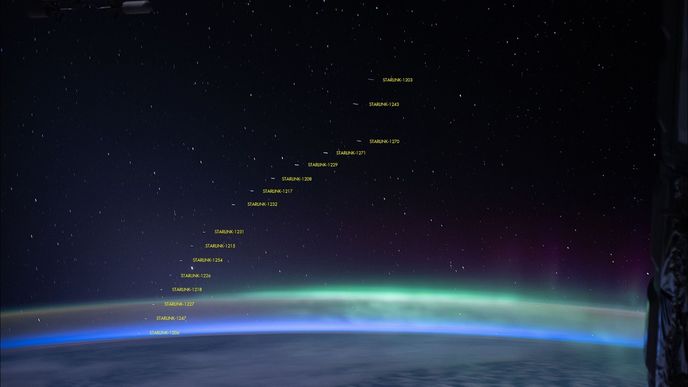 Družice StarLink s polární září v pozadí.