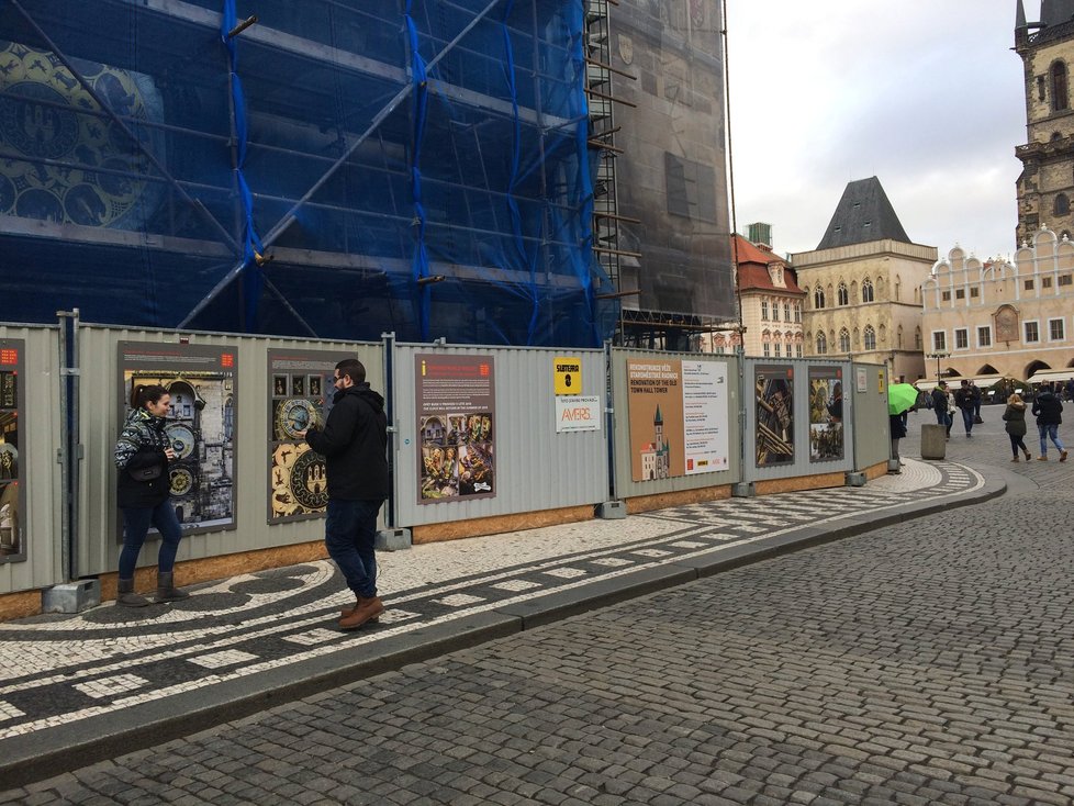 Přestože na orloj není přes lešení vidět, stále se o něj zajímají turisté.