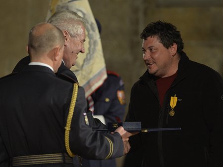 Robert Sedláček ve fleecové mikině za pětistovku přebírá od prezidenta medaili Za zásluhy. Oceněn byl v roce 2014.