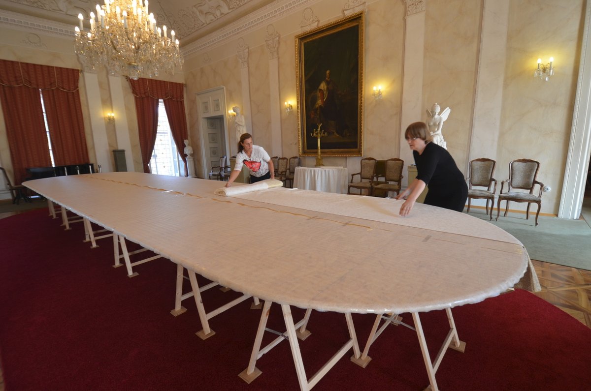 Hlavní část expozice připravují Libuše Ruiozová a Jitka Bukovjanová. Na devět metrů dlouhý stůl pokládají damaškový ubrus zdobený zlatem.