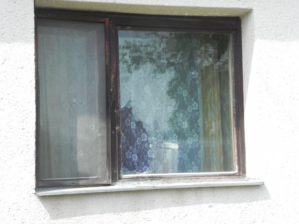 Prostřílená okna domku, u kterého došlo k tragédii. Zásahovka našla uvnitř mrtvého střelce.