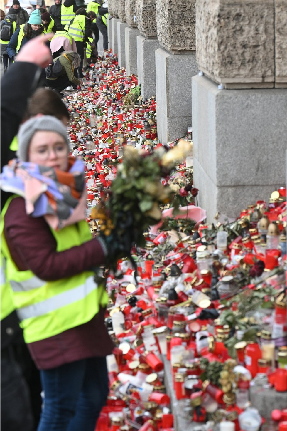 Dobrovolníci sbírají a ukládají svíčky a květiny z pietního místa u hlavní budovy Filozofické fakulty Univerzity Karlovy, 15. ledna 2024, Praha.
