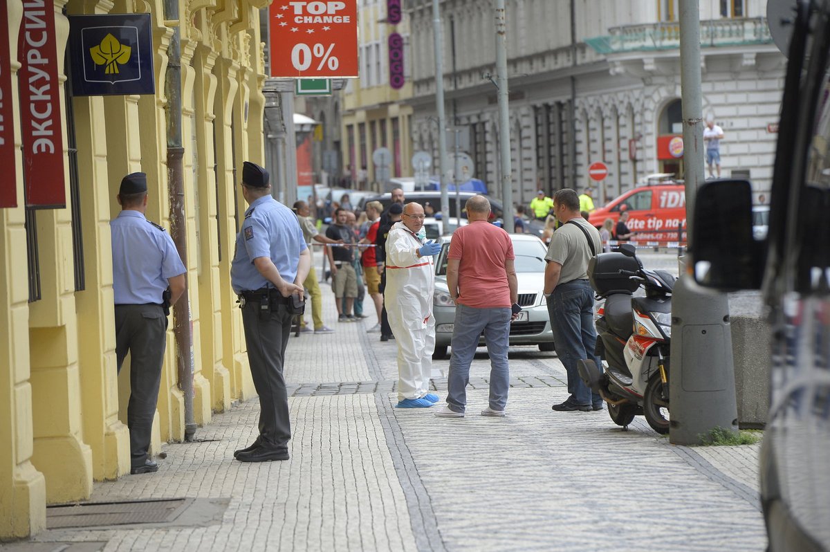 Policista ve speciálním obleku zajišťoval stopy.