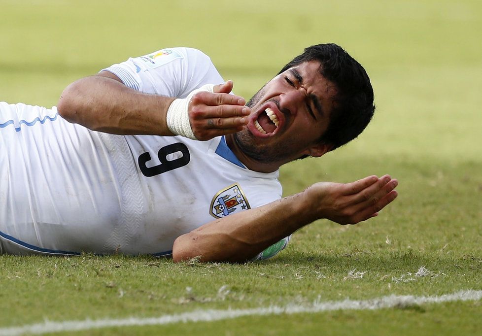 Útočník Luis Suárez předstírá bolest poté, co se zakousl do ramena italského obránce Chielliniho. Jeden z nejlepších světových útočníků předvedl v závěru utkání s Itálií další velký zkrat ve svojí kariéře, za který ho však sudí nepotrestal.