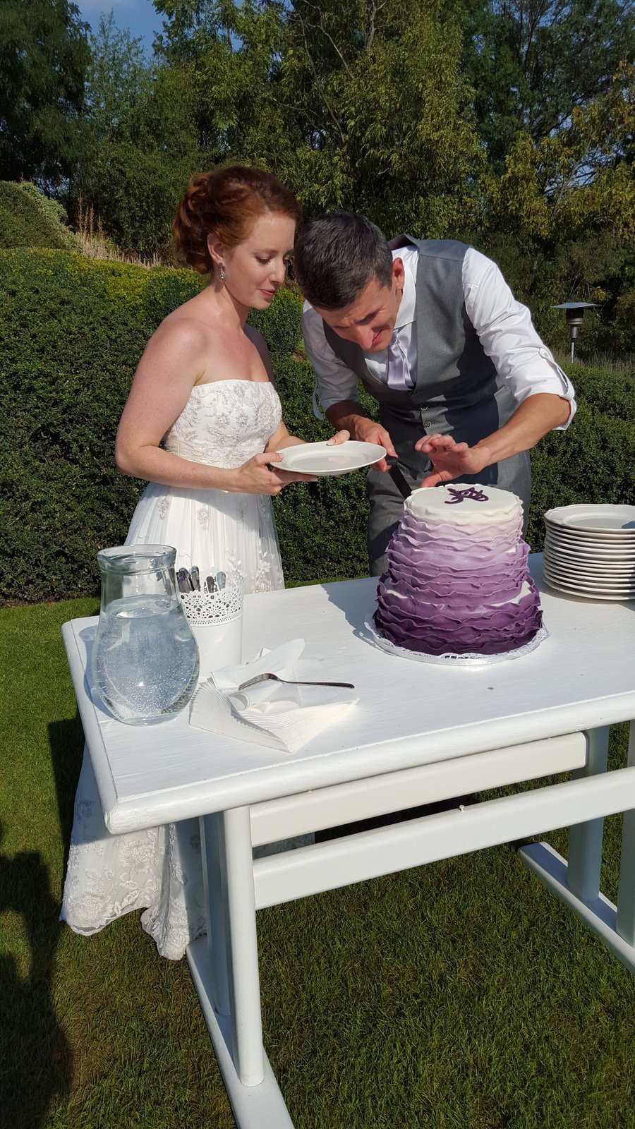 Novomanželé krájí krásný fialový dort.