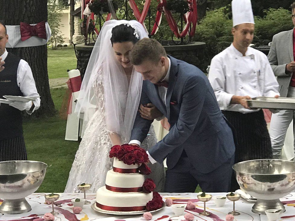Novomanželé Tereza N. B. (26) a Ondřej N. (24) krájí tříposchoďový dort.