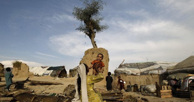 Matka drží v dlaních dítě ve slumu v pákistánském Islamabádu