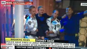 Policisté vynášejí otřesenou rukojmí, které se podařilo uprchnout z kavárny v Sydney