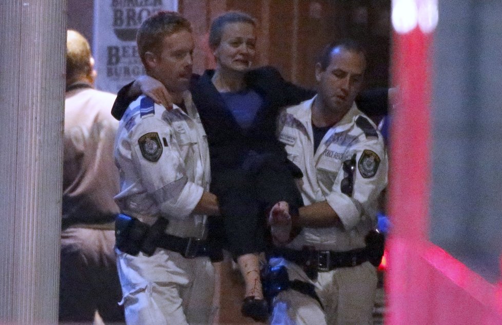 Záchranáři nesou zraněnou ženu z kavárny ze Sydney