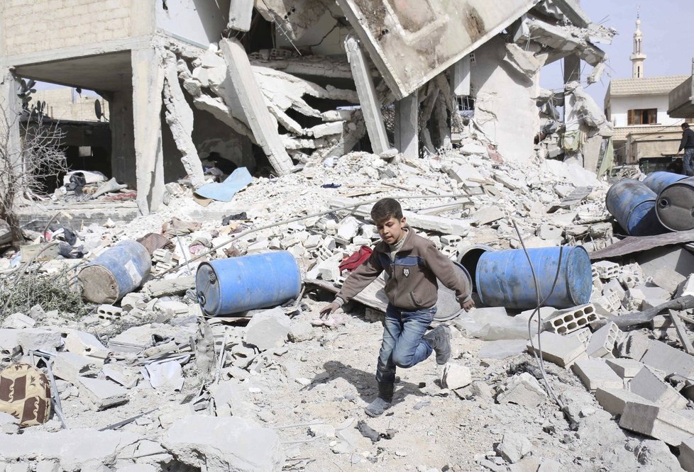 Chlapec prohánějící se v troskách syrského města nedaleko metropole Damašku