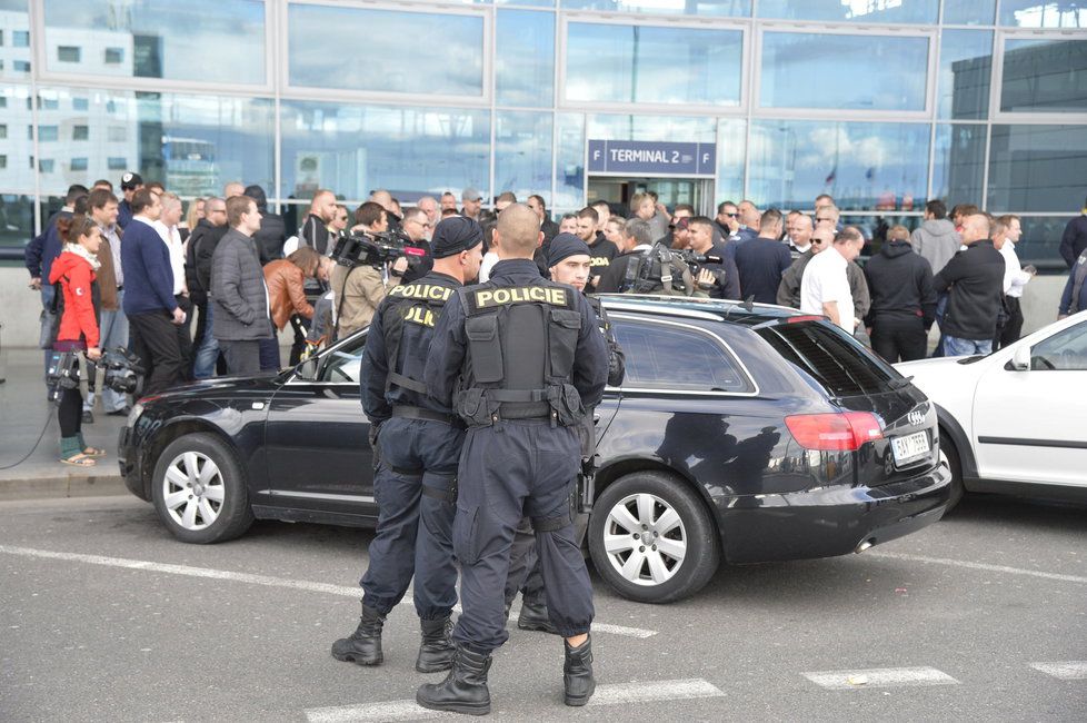 Taxikáře na letišti v Praze krotí policisté. Na vozy řidičů Uberu letí samolepky s nápisem Ilegal Transport.