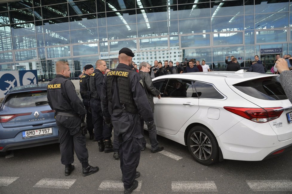 Taxikáře na letišti v Praze krotí policisté. Na vozy řidičů Uberu letí samolepky s nápisem Ilegal Transport.