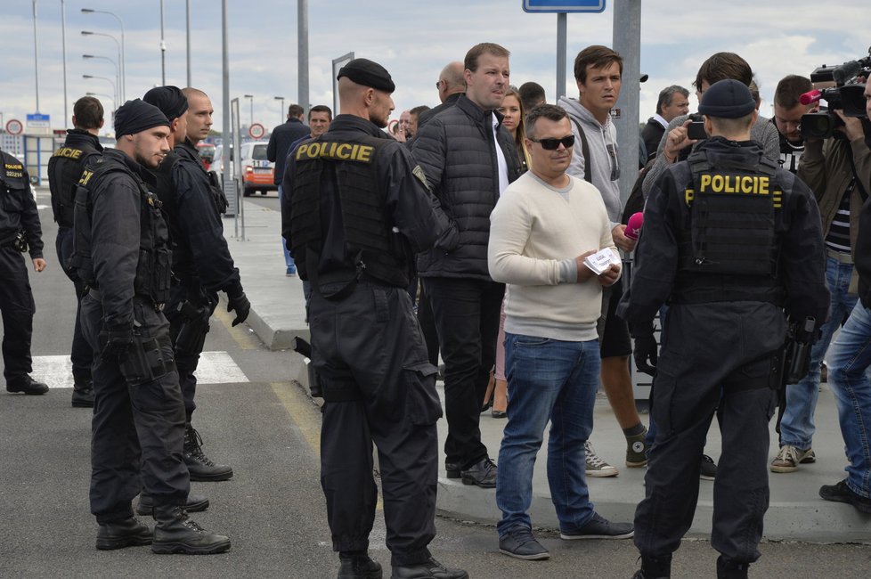 Taxikáře na letišti v Praze krotí policisté. Na vozy řidičů Uberu lepí samolepky s nápisem Ilegal Transport.